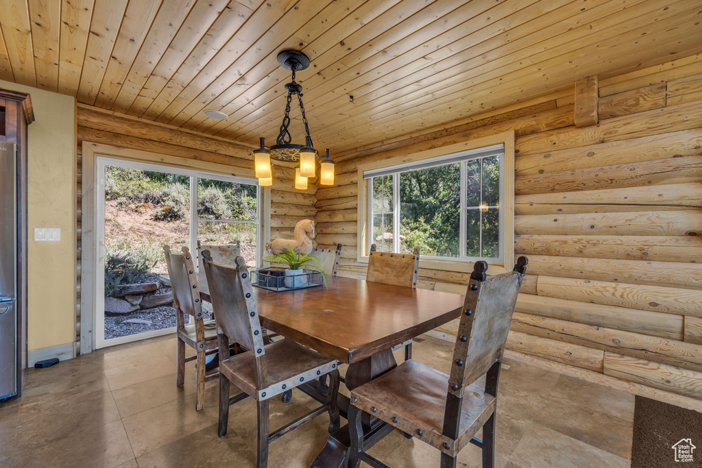 Dining room featuring log walls and wooden ceiling