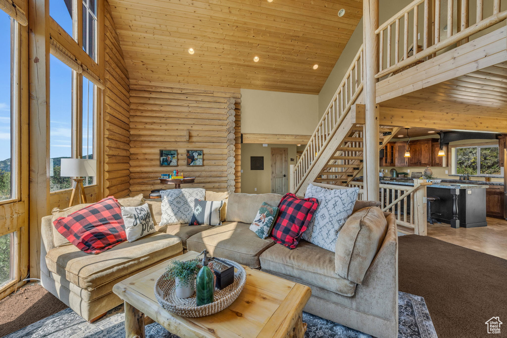 Living room with wooden ceiling, high vaulted ceiling, and rustic walls