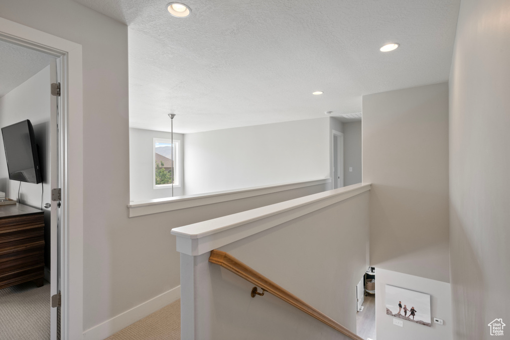 Corridor featuring a textured ceiling and carpet floors