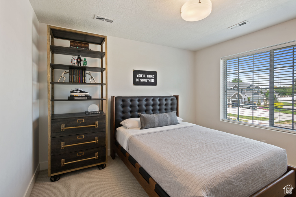 Bedroom featuring light colored carpet and a textured ceiling