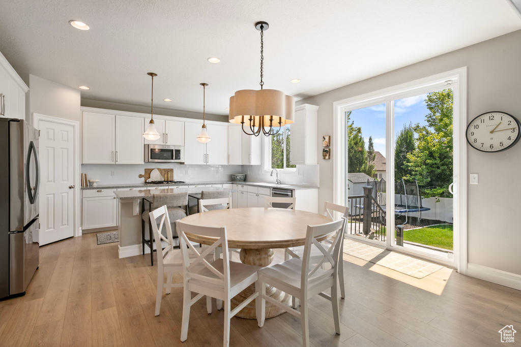 Dining space with light wood-type flooring, a wealth of natural light, and an inviting chandelier