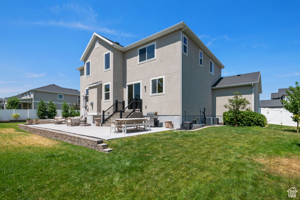 Rear view of property with a lawn, a patio, and central air condition unit