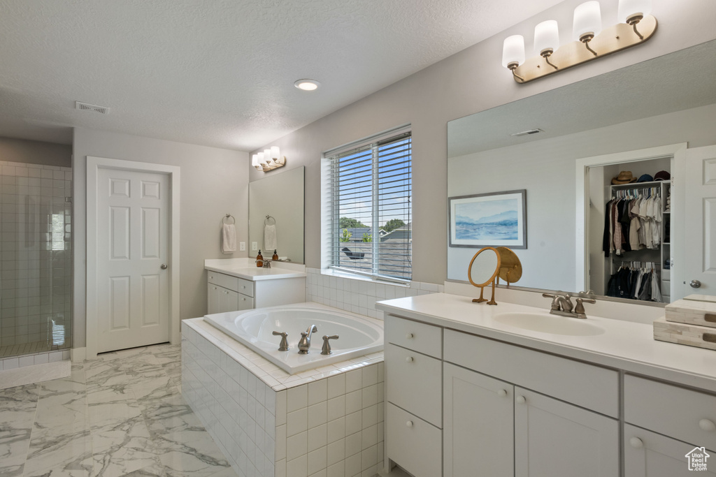 Bathroom featuring vanity, a textured ceiling, and shower with separate bathtub