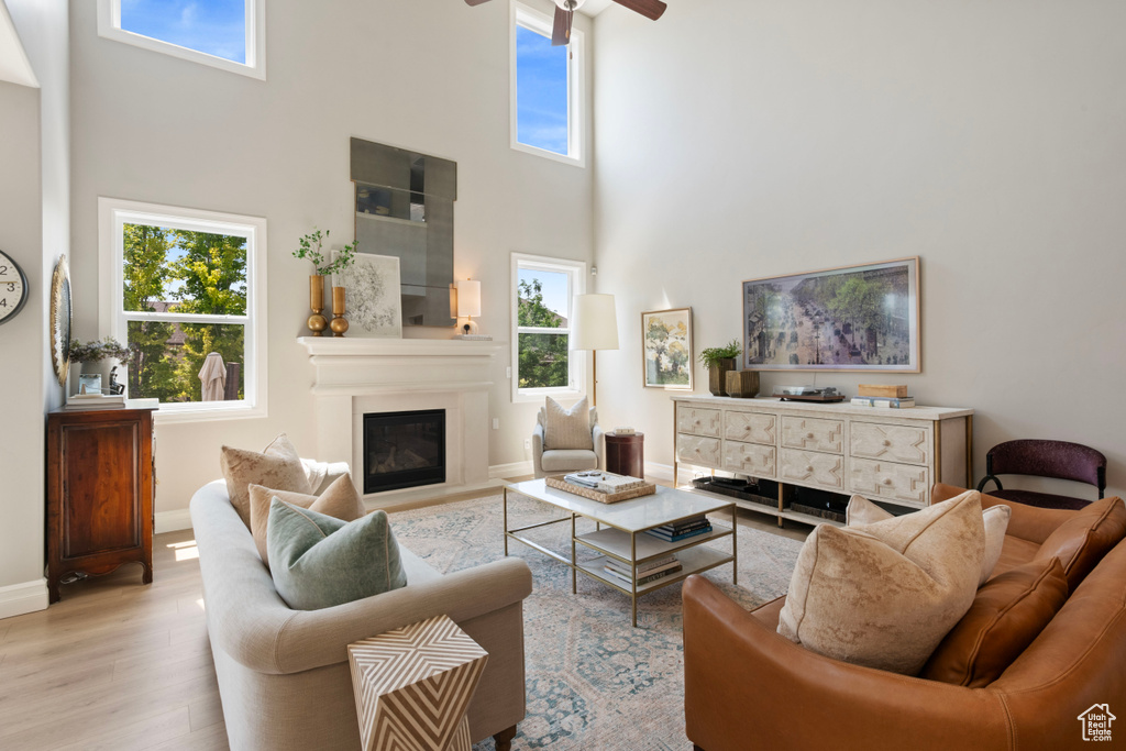 Living room featuring light wood-type flooring, a high ceiling, and a healthy amount of sunlight