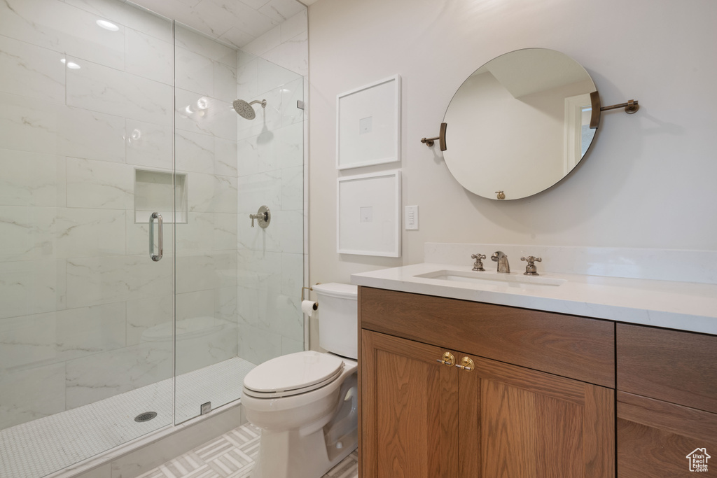 Bathroom with toilet, a shower with door, and vanity