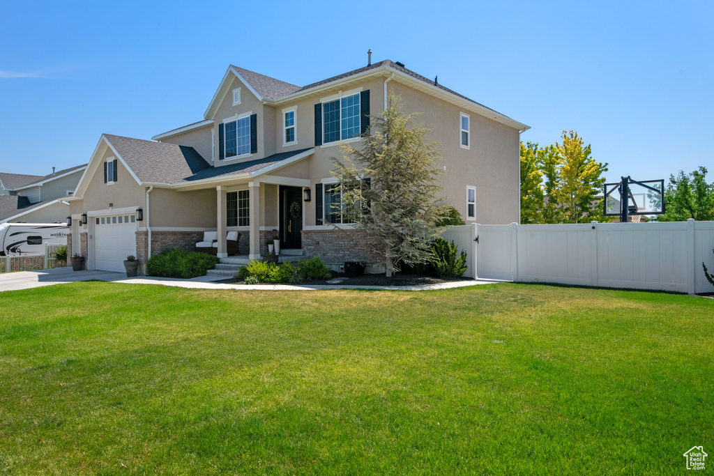 View of front facade with a garage, covered porch, and a front yard