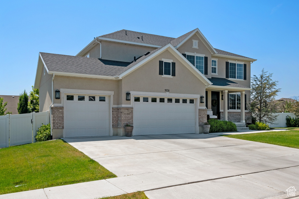 Craftsman inspired home featuring a garage and a front lawn