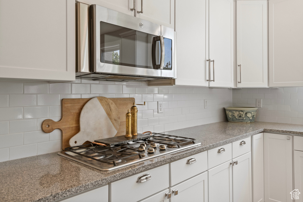 Kitchen featuring tasteful backsplash, stainless steel appliances, and white cabinets