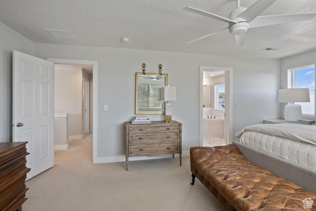 Bedroom with a textured ceiling, ceiling fan, ensuite bathroom, and multiple windows