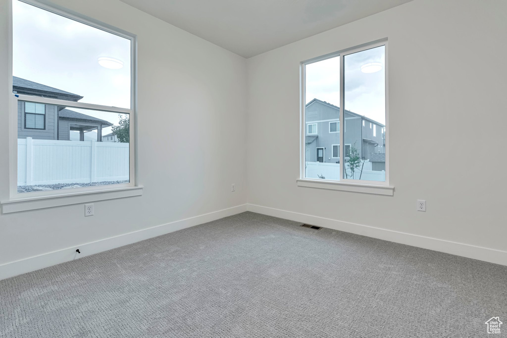 Empty room featuring plenty of natural light and carpet flooring