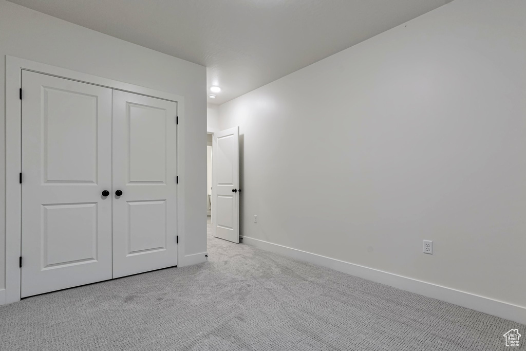 Unfurnished bedroom featuring light colored carpet and a closet