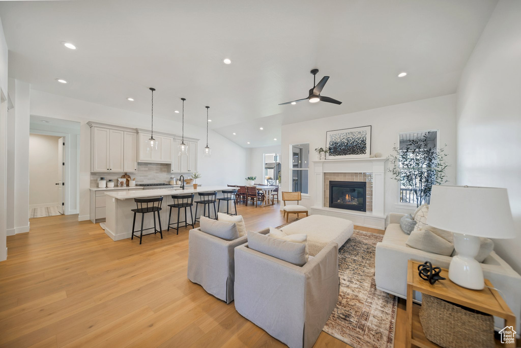 Living room with ceiling fan, light wood-type flooring, and a tile fireplace