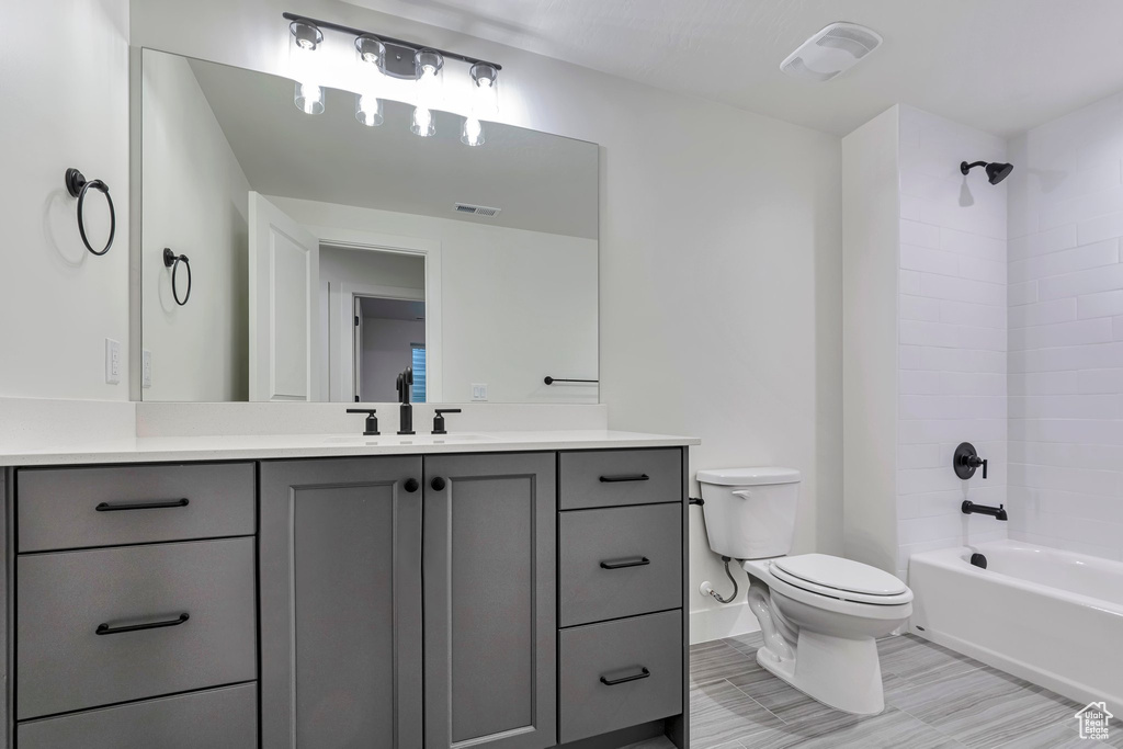 Full bathroom featuring toilet, tiled shower / bath combo, and vanity