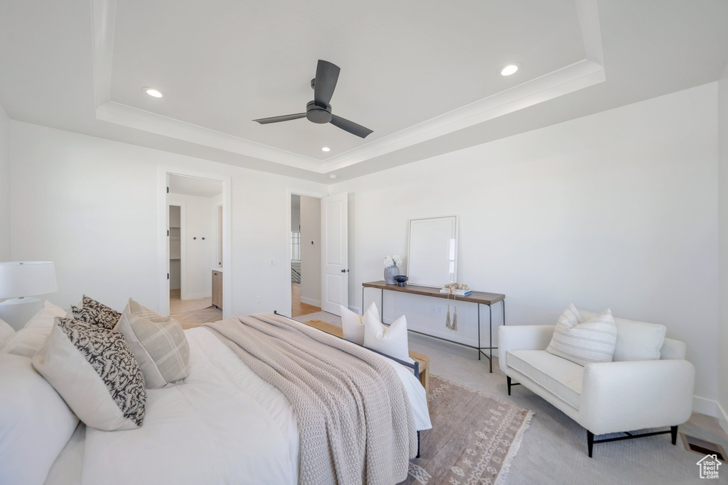 Bedroom featuring a raised ceiling, ensuite bathroom, and ceiling fan