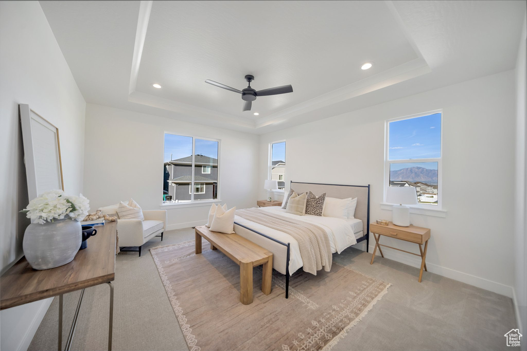 Bedroom featuring ceiling fan, light carpet, and a tray ceiling