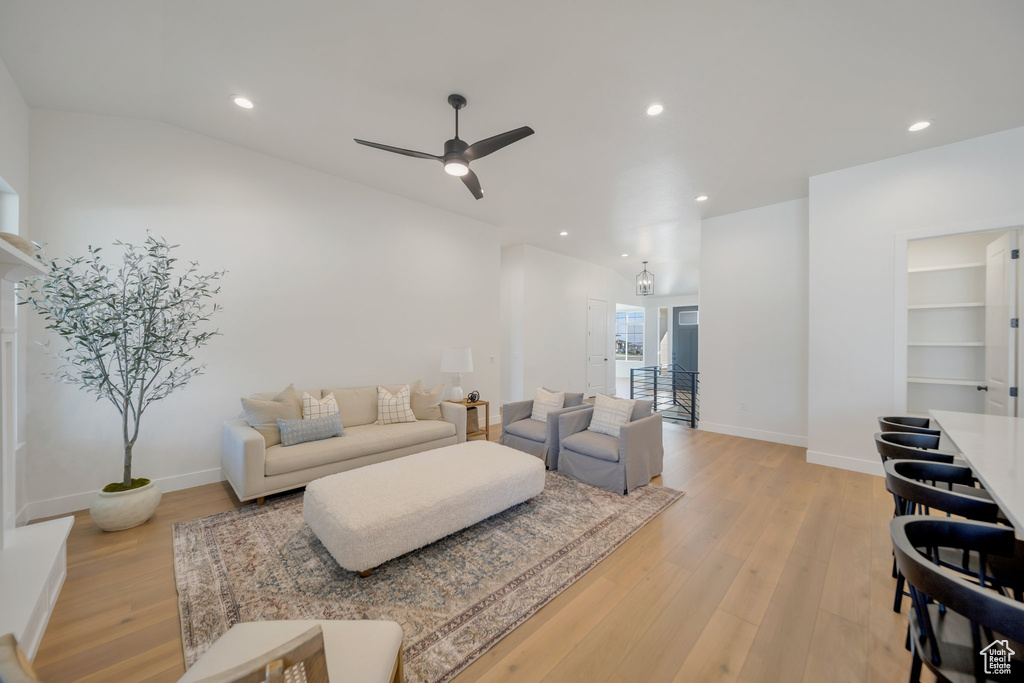 Living room featuring light wood-type flooring, ceiling fan, and vaulted ceiling