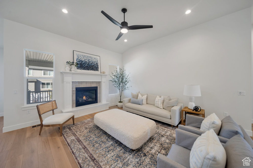 Living room with a fireplace, ceiling fan, and light hardwood / wood-style floors