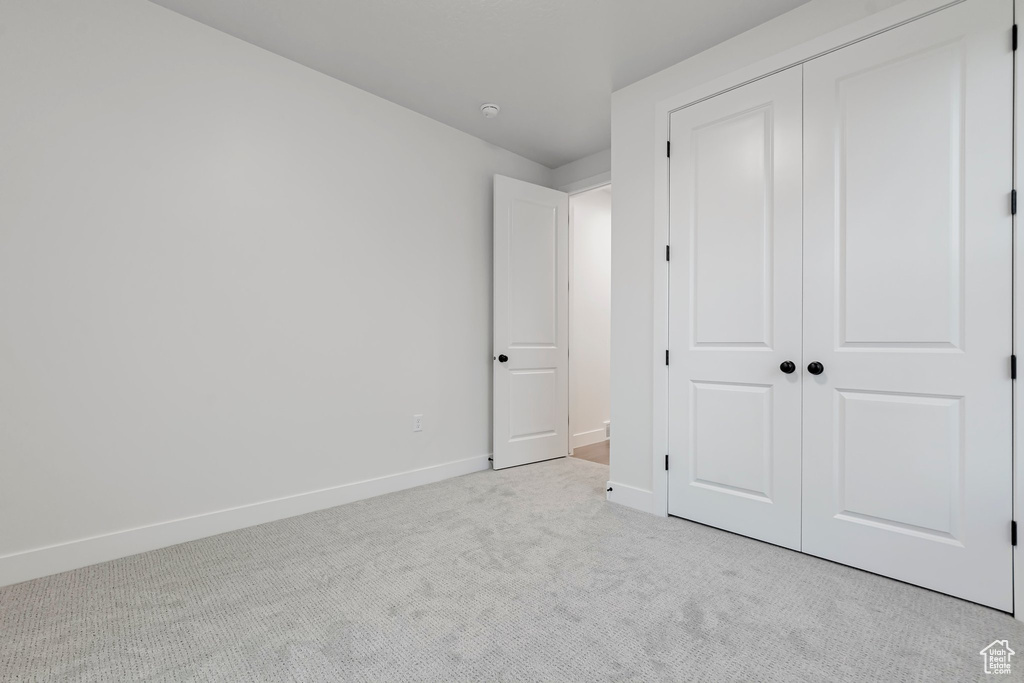 Unfurnished bedroom featuring light carpet and a closet