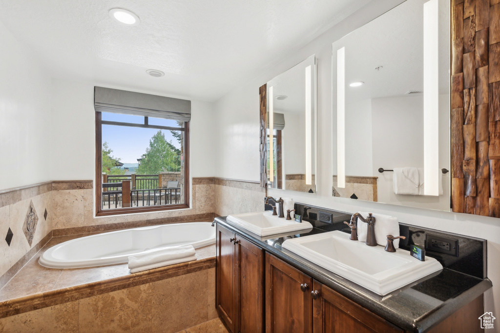 Bathroom with vanity and tiled bath