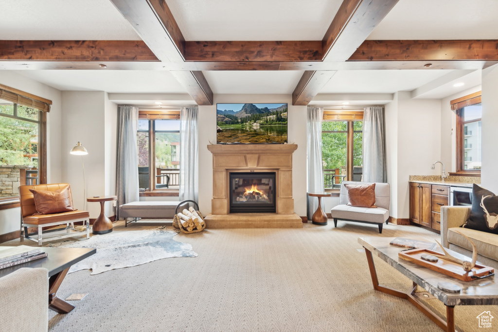 Carpeted living room featuring beamed ceiling, a wealth of natural light, and sink