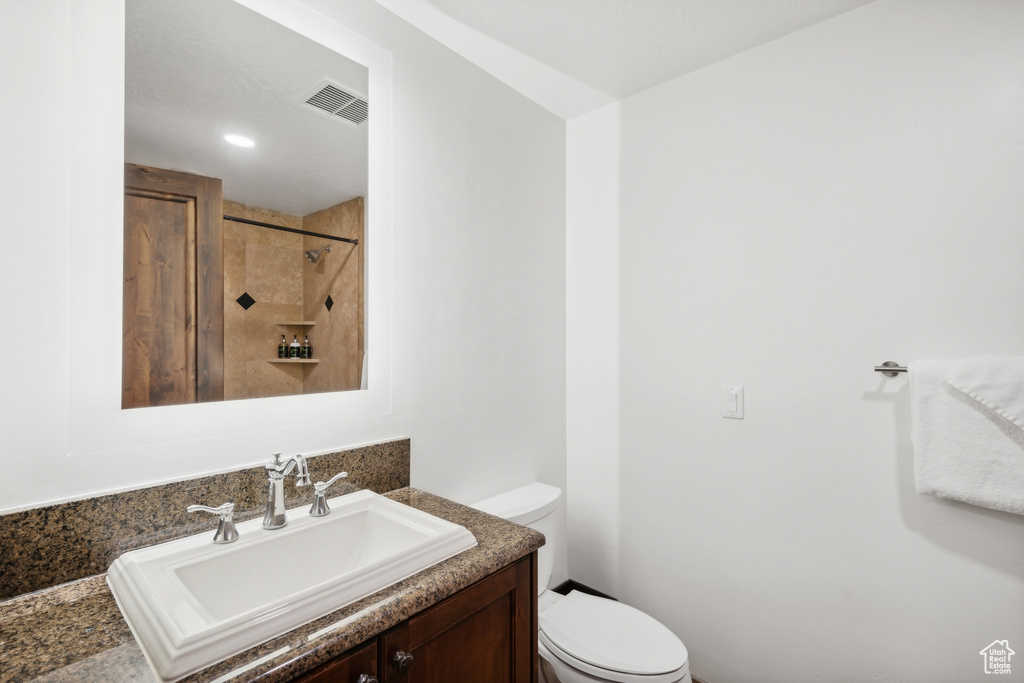 Bathroom featuring vanity, toilet, and a tile shower