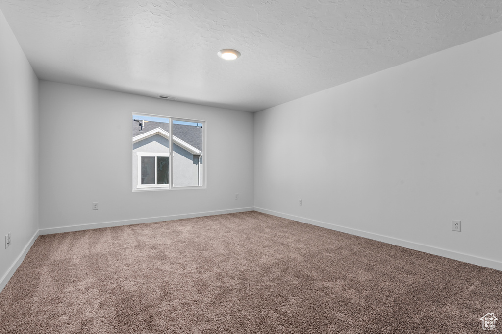 Carpeted empty room with a textured ceiling