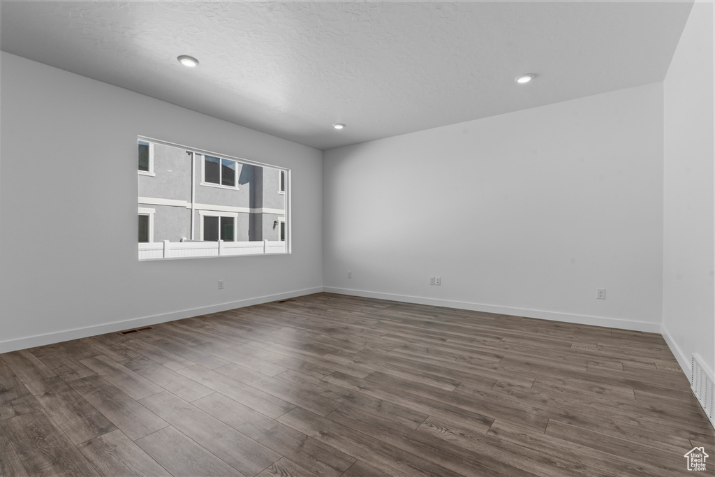 Empty room with a textured ceiling and hardwood / wood-style floors