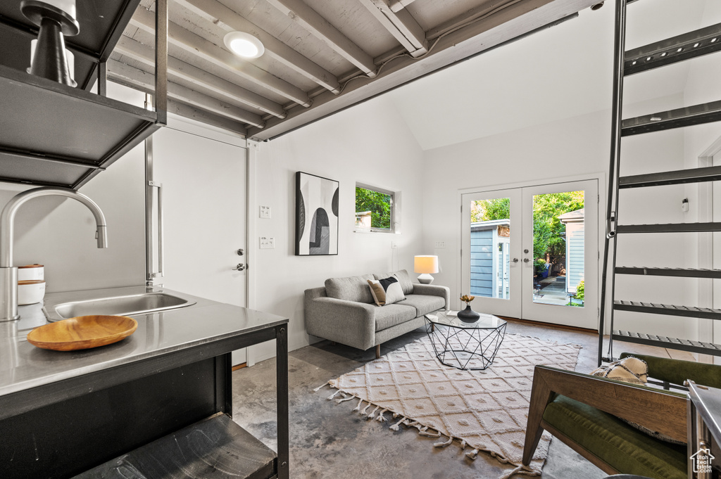 Living room featuring concrete flooring, sink, french doors, and lofted ceiling