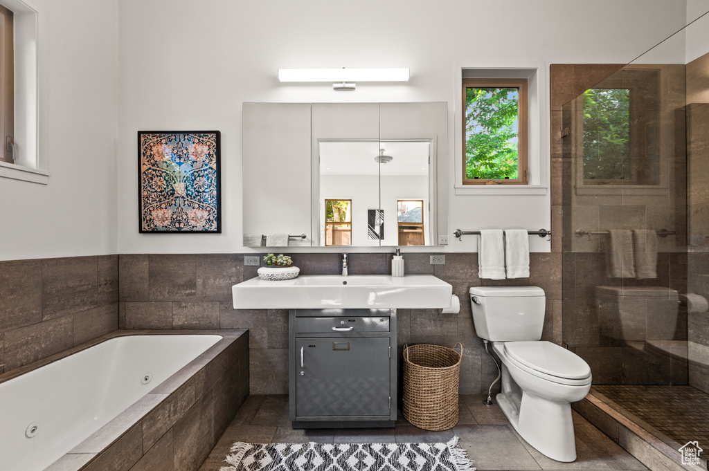 Full bathroom featuring toilet, tile patterned flooring, vanity, tile walls, and shower with separate bathtub