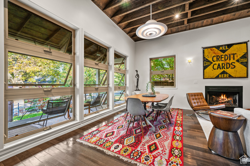 Dining area with dark hardwood / wood-style flooring, a healthy amount of sunlight, and beam ceiling