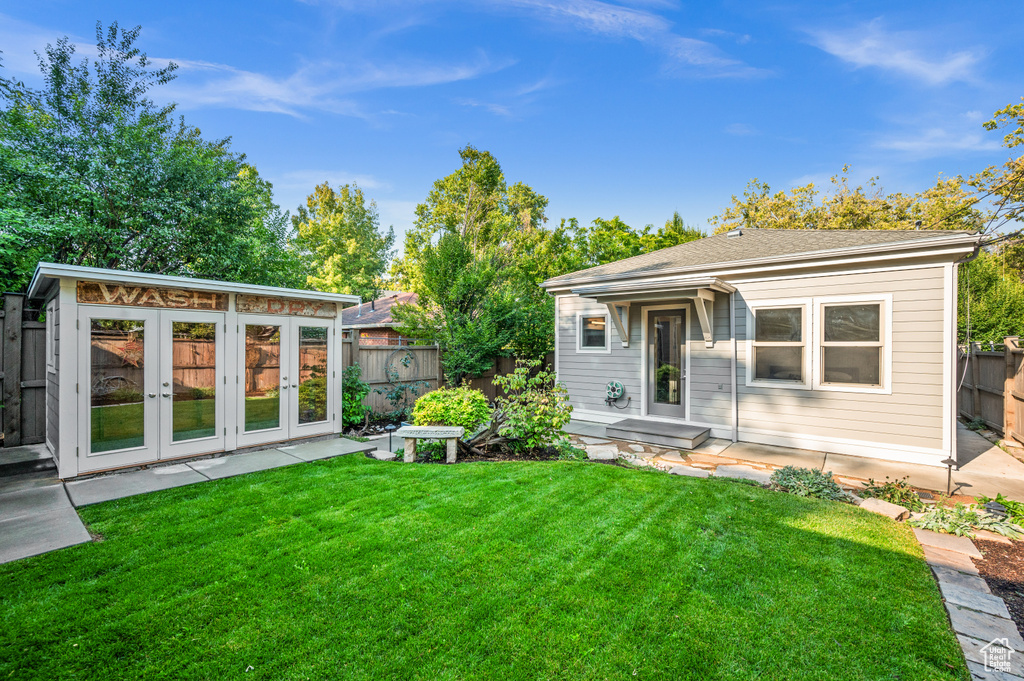 Back of property with a yard, an outdoor structure, and french doors