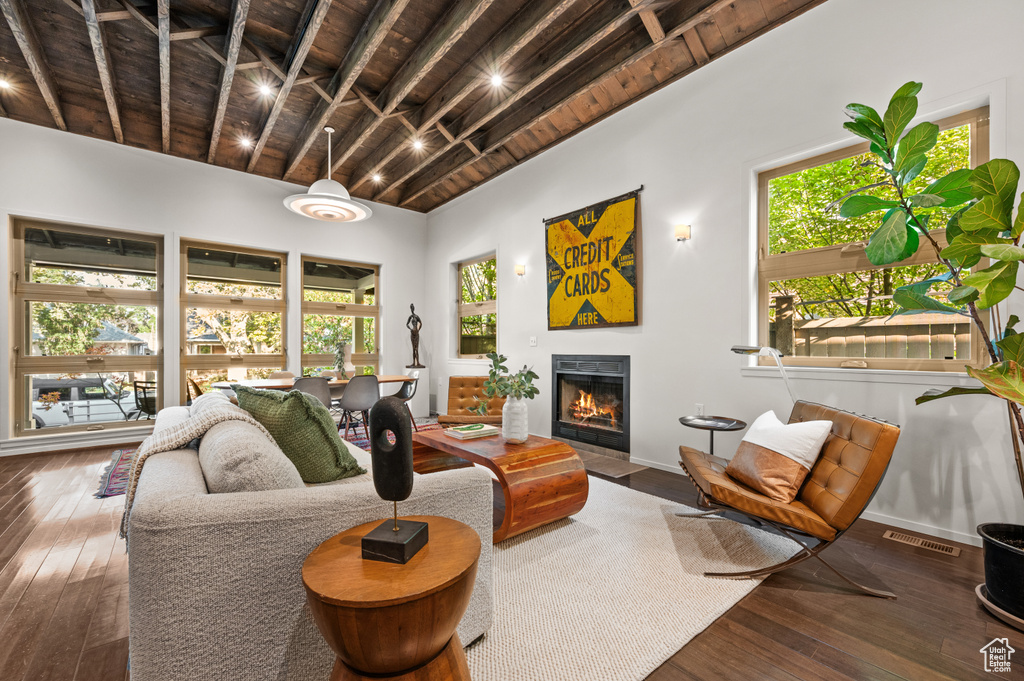 Living room with dark wood-type flooring, wood ceiling, a wealth of natural light, and beam ceiling