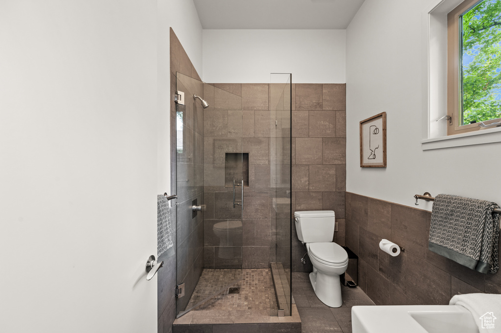 Bathroom with toilet, a shower with shower door, and tile patterned floors