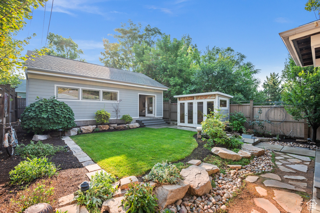 Back of property featuring an outdoor structure and a yard