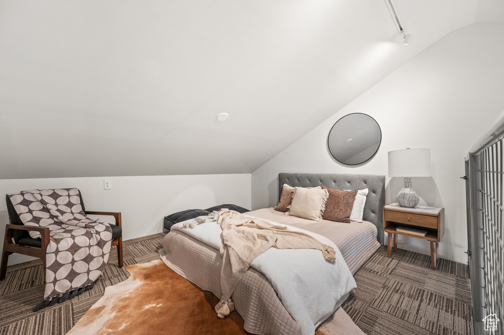 Bedroom with vaulted ceiling and dark colored carpet