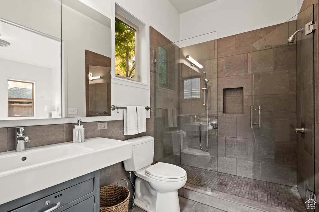 Bathroom with vanity, walk in shower, toilet, tile patterned floors, and decorative backsplash