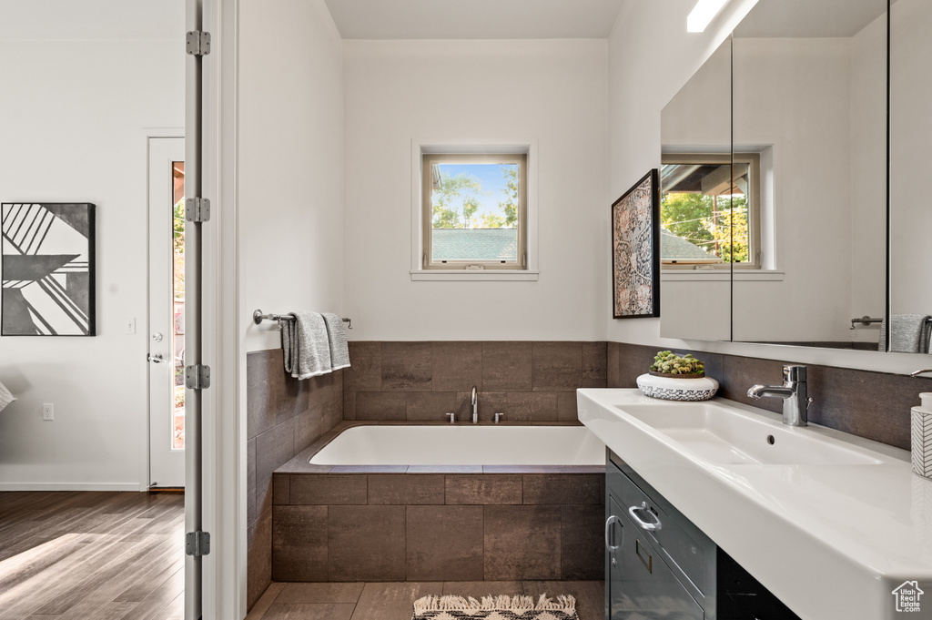 Bathroom with vanity, hardwood / wood-style flooring, and tiled bath