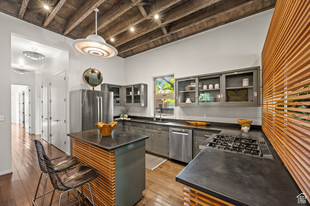 Kitchen with a center island, sink, hanging light fixtures, appliances with stainless steel finishes, and beam ceiling