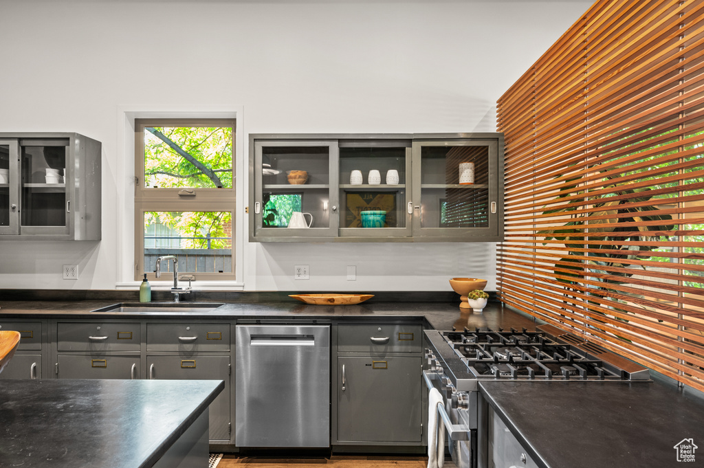 Kitchen with gray cabinets, high end stainless steel range oven, and sink