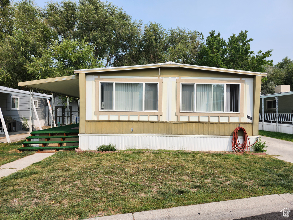 Manufactured / mobile home featuring a front lawn and a carport