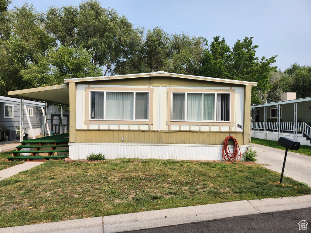 Manufactured / mobile home featuring a front lawn and a carport