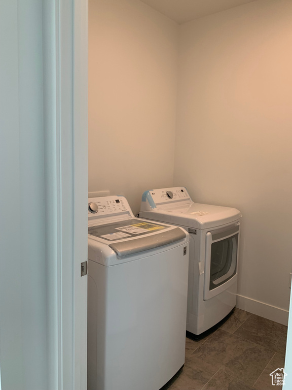 Clothes washing area with dark tile patterned flooring and washing machine and dryer