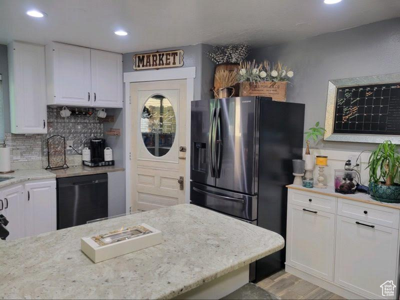 Kitchen featuring light wood-type flooring, white cabinetry, dishwasher, decorative backsplash, and stainless steel refrigerator with ice dispenser