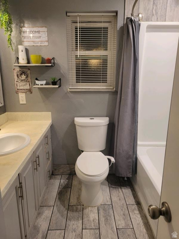 Full bathroom with vanity, toilet, wood-type flooring, and shower / tub combo with curtain