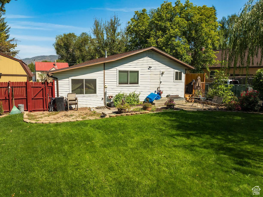 Rear view of property with a mountain view and a lawn