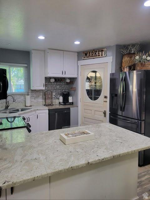 Kitchen featuring black appliances, sink, wood-type flooring, and white cabinetry