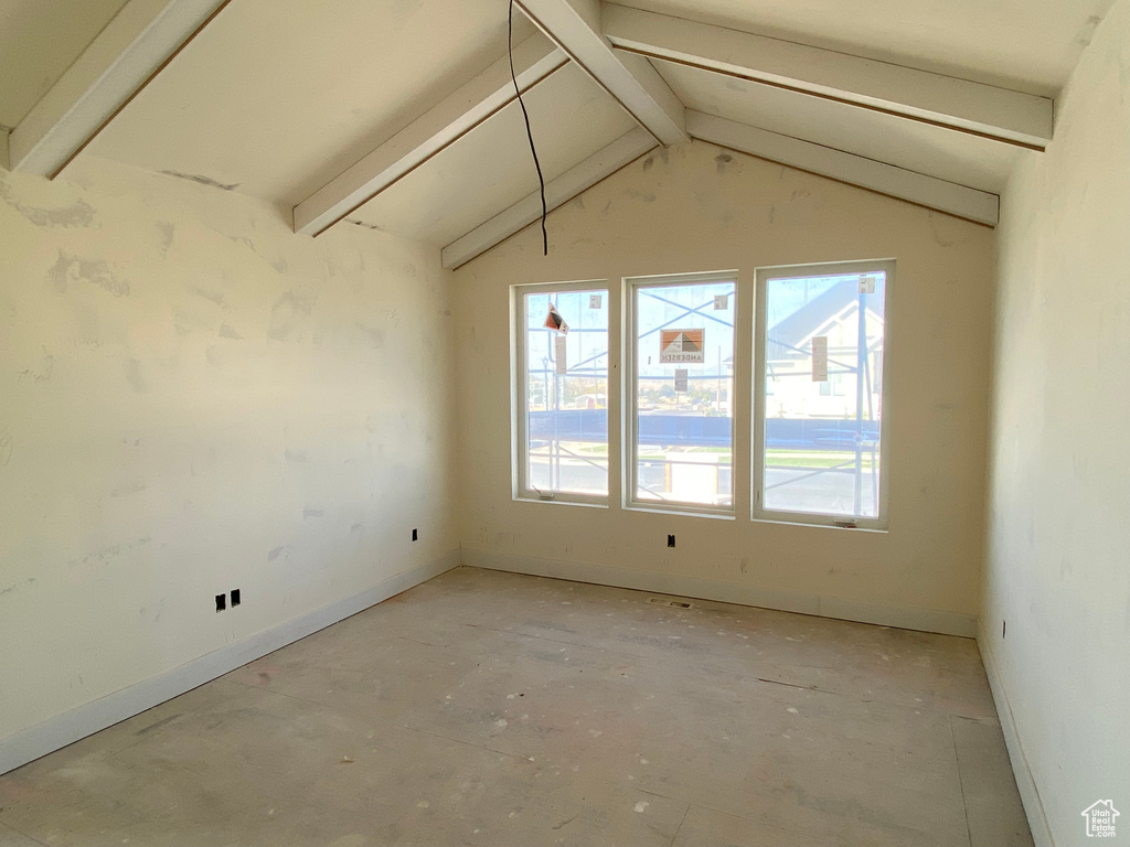 Spare room featuring lofted ceiling with beams