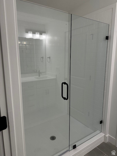 Bathroom featuring walk in shower, sink, and tile patterned floors