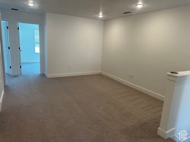 Unfurnished room with a textured ceiling and carpet floors