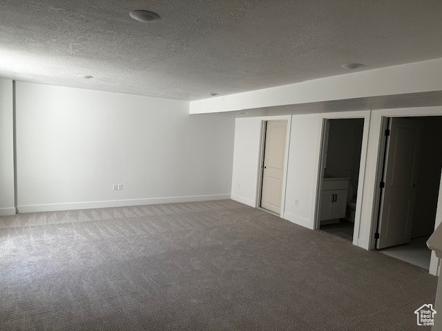 Unfurnished bedroom featuring a textured ceiling, carpet, and ensuite bathroom